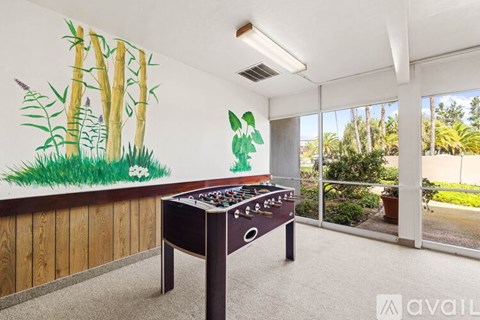 A foosball table in a room with a painted forest mural on the wall.
