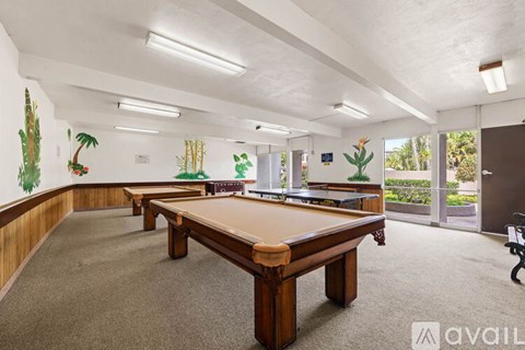 A room with a pool table and a wall mural of palm trees.