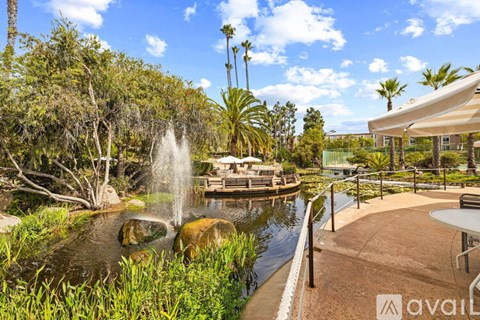 A fountain in the middle of a pond surrounded by greenery.