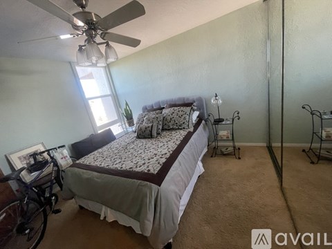 A bedroom with a bed, a fan, and a bicycle.