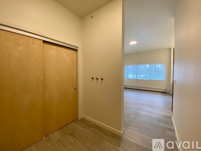 A spacious room with wooden flooring and a built-in bench under a window.