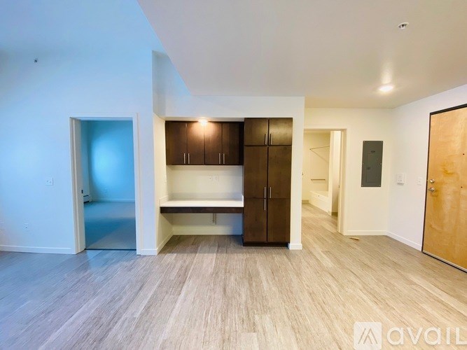 A spacious room with wooden flooring and a built-in bench under a window.