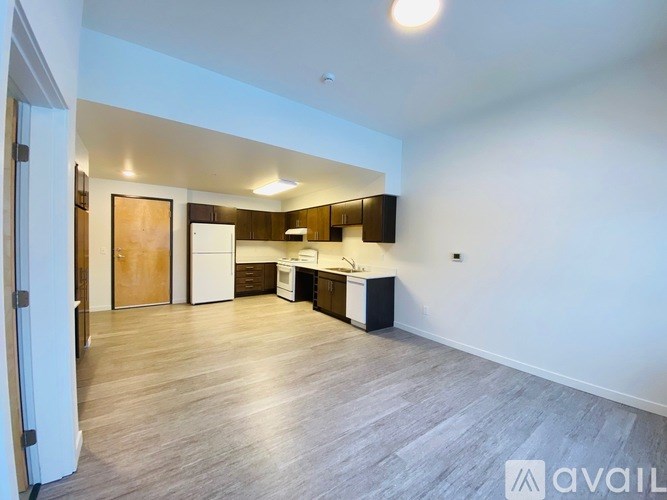 A spacious kitchen with wooden floors and white walls.