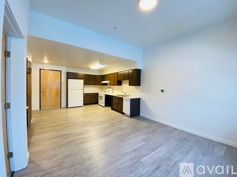 A spacious kitchen with wooden floors and white walls.