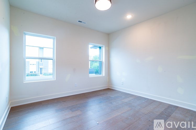 A room with wooden floors and two windows.