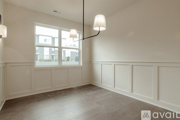 A well-lit room with a large window and a wooden floor.