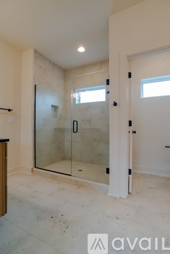 A bathroom with a glass shower door and a window.