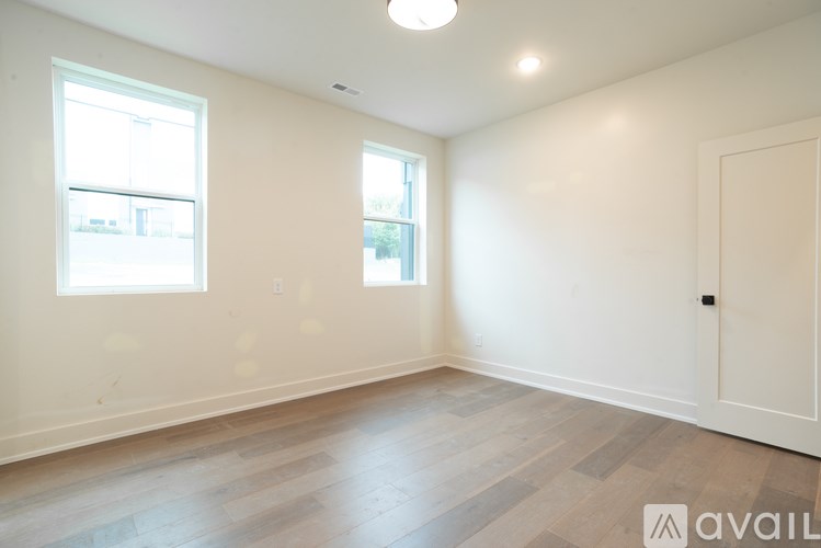 A room with wooden flooring and two windows.