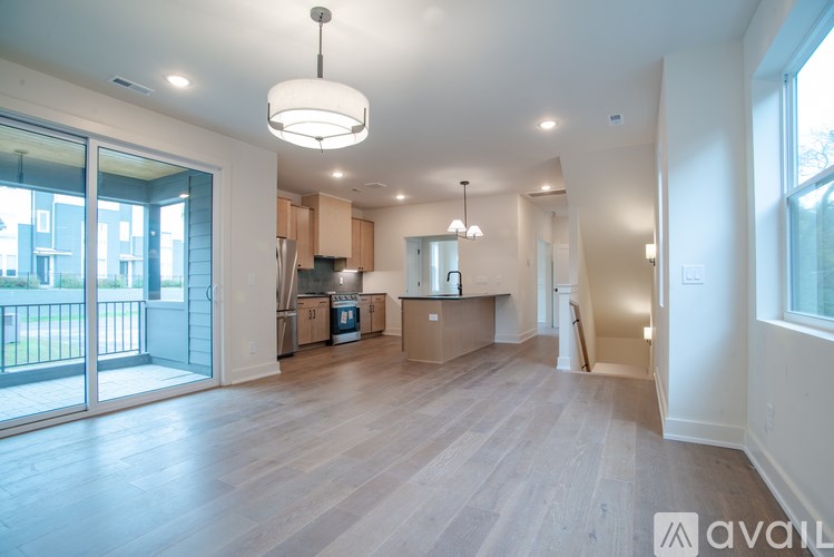 A large, empty room with wooden floors and a kitchen area in the background.