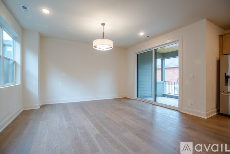 A spacious room with wooden flooring and a hanging light fixture.