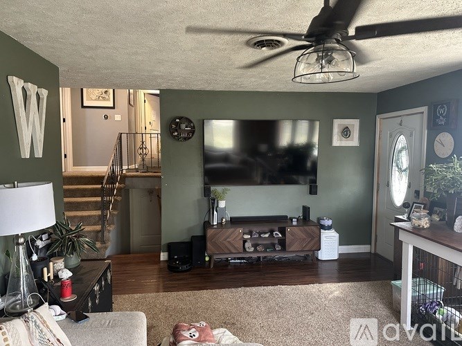 A living room with a couch, a coffee table, a TV, and a staircase.