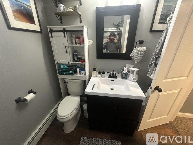 A bathroom with a toilet, sink, and mirror.