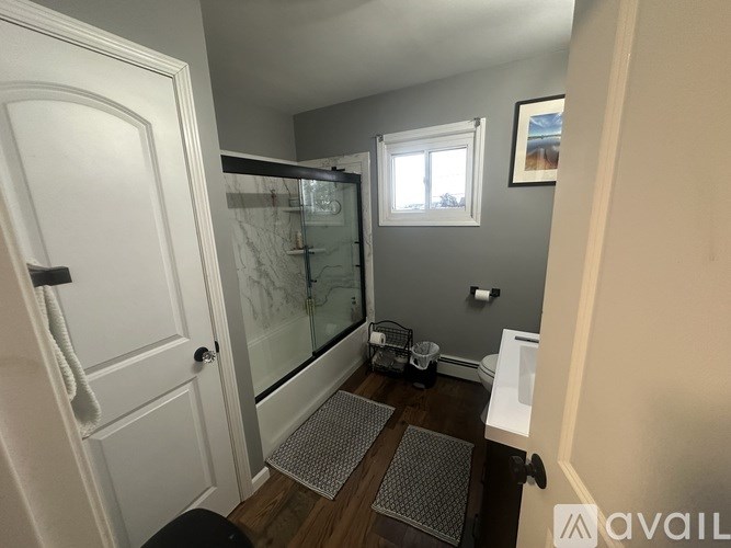 A bathroom with a glass shower door and a white door.