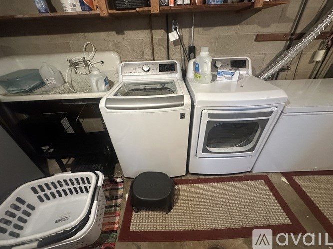 A white dishwasher and dryer are on a shelf in a laundry room.