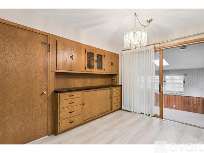 A wooden kitchen with a chandelier hanging from the ceiling.