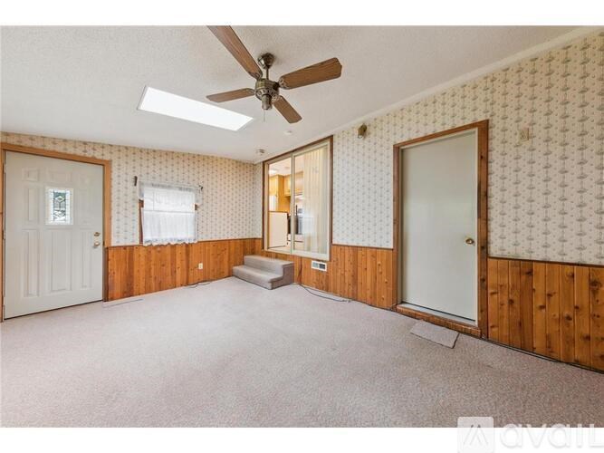 A room with a ceiling fan and patterned wallpaper.