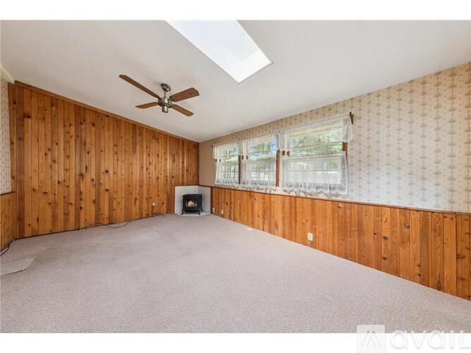 A room with wooden walls and a fireplace with a skylight above it.
