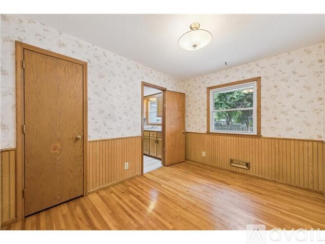 A room with wood floors and a wallpapered wall with a window.
