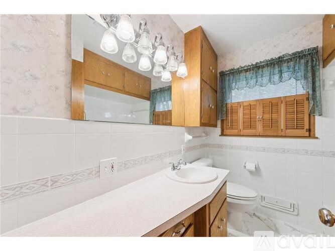 A bathroom with a sink, toilet, and wooden cabinets.