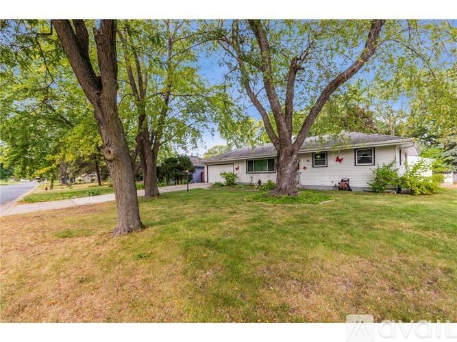 A house with a green lawn and trees in front of it.