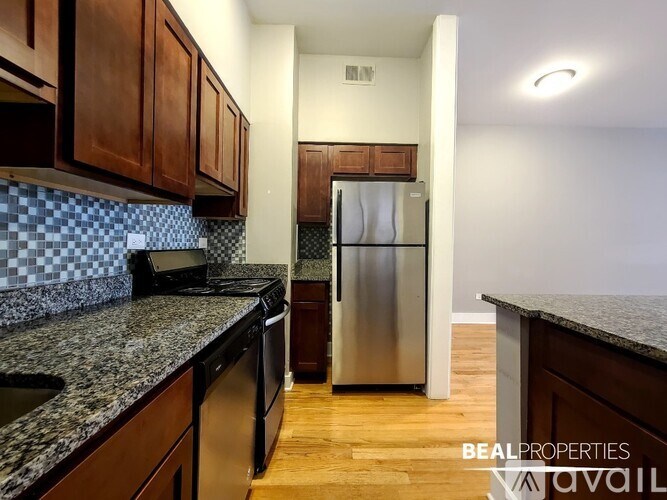 A kitchen with a granite counter top and a stainless steel refrigerator.