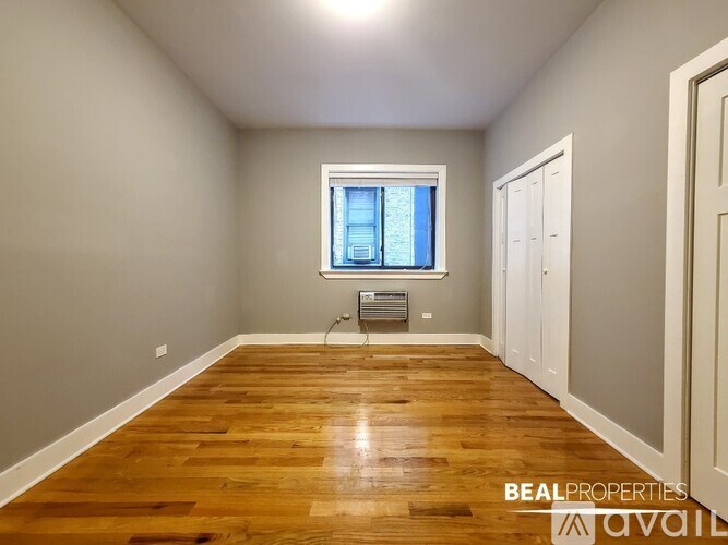A room with wooden floors and a window with a view of a building outside.