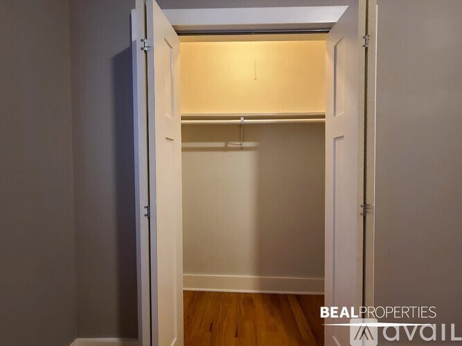 A white door is open to a room with a wooden floor.