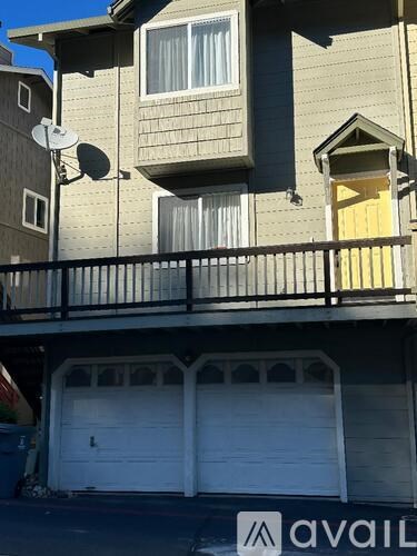 A two-story house with a garage and a satellite dish on the roof.