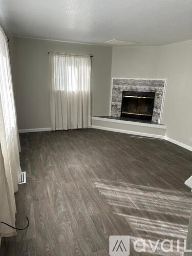 A living room with a fireplace and a window with curtains.