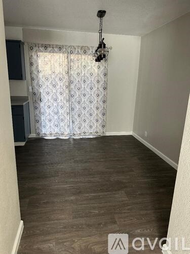 A room with wooden flooring and a patterned curtain.