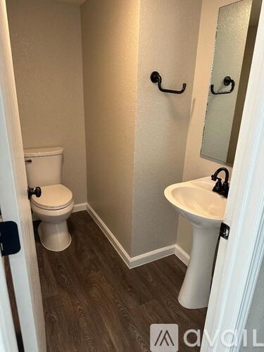 A small bathroom with a toilet, sink and mirror.