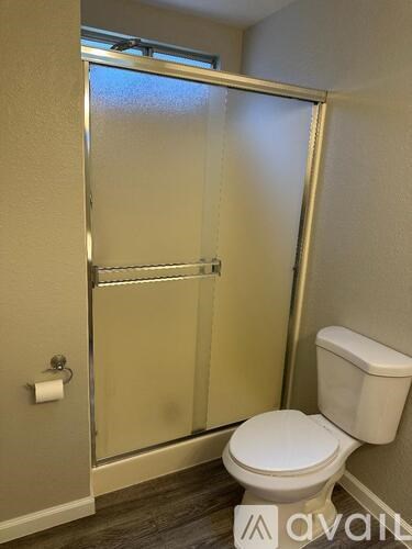 A white toilet in a small bathroom with a glass shower door.