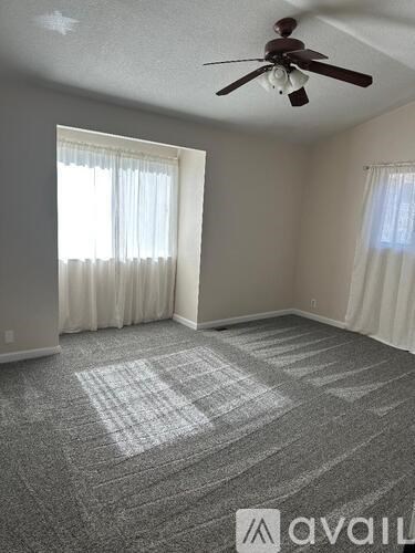 A room with a ceiling fan and carpeted floor.