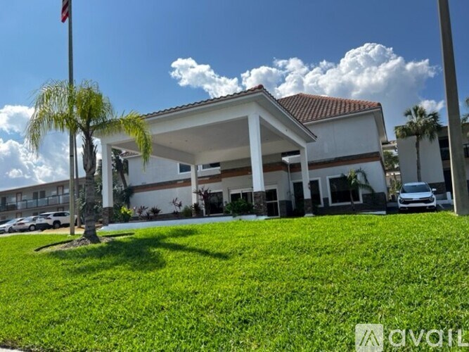 A white building with a flag on top and a palm tree in front.