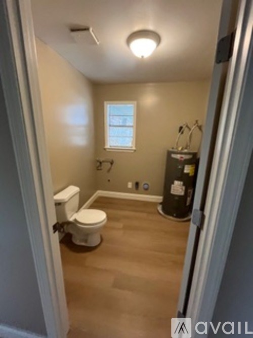 A bathroom with a toilet, sink, and a window.