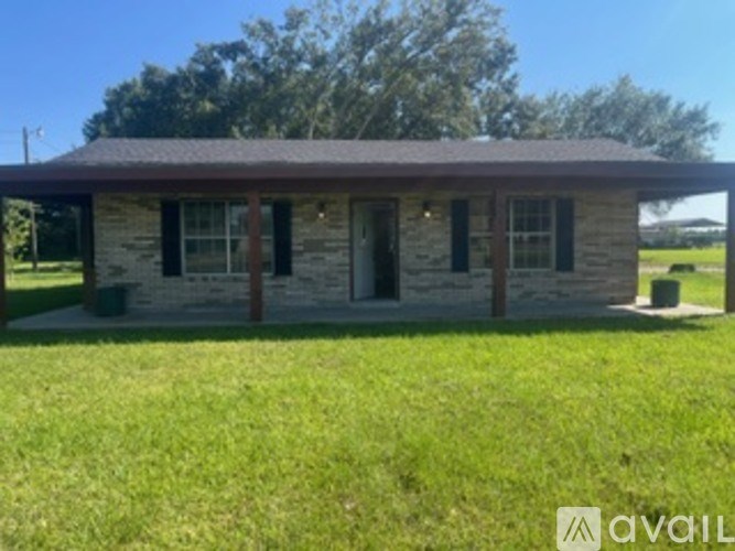 A small house with a brown roof and a green lawn in front.