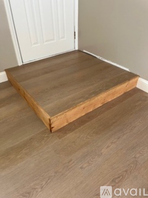 A wooden step in a room with white walls.