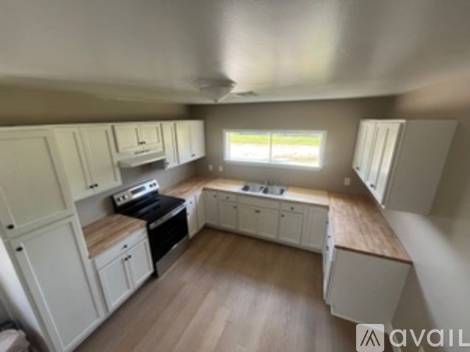A kitchen with white cabinets and wooden floors is available for rent.