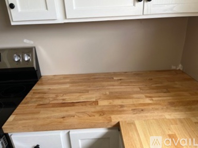 A kitchen with white cabinets and a wooden countertop.