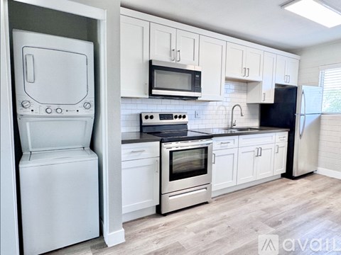 A kitchen with white cabinets and black countertops.
