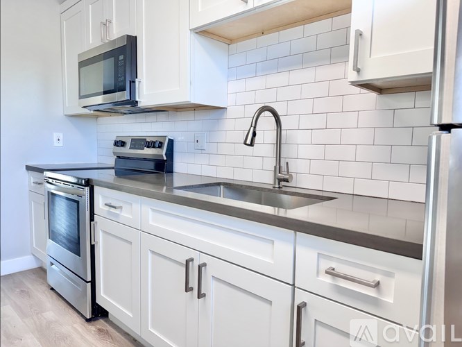A kitchen with white cabinets and a black microwave above the stove.