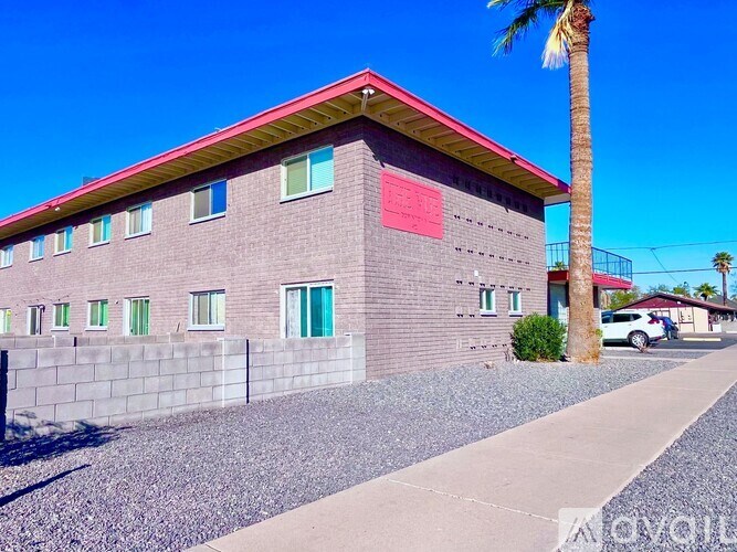 A red building with a palm tree in front.