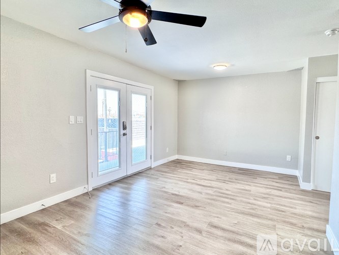 A room with a ceiling fan and sliding glass doors.