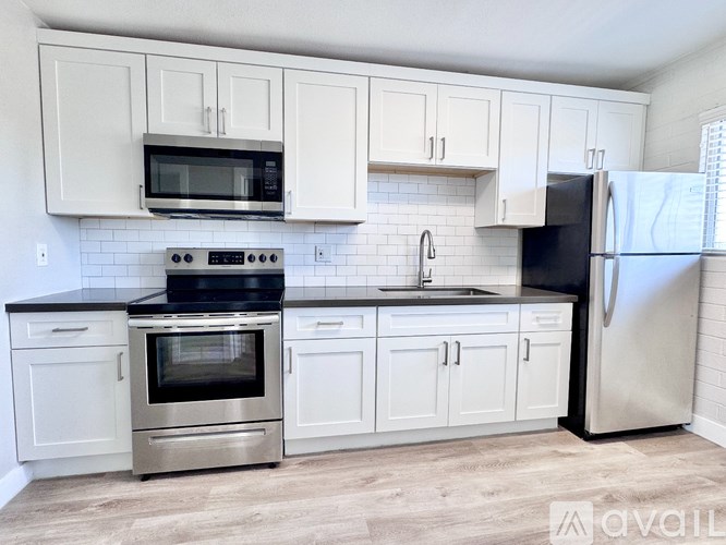A kitchen with white cabinets and a black refrigerator.