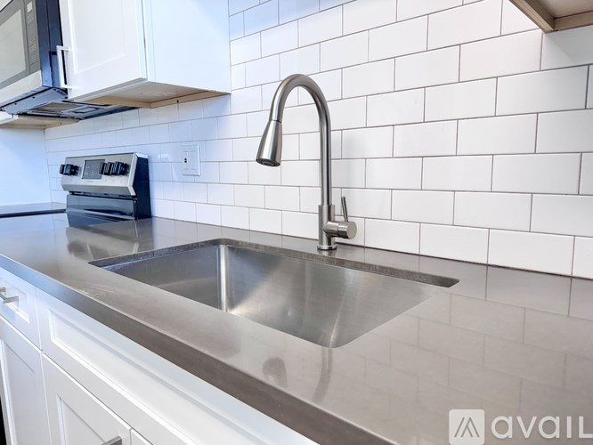A modern kitchen with a stainless steel sink and white tiled backsplash.