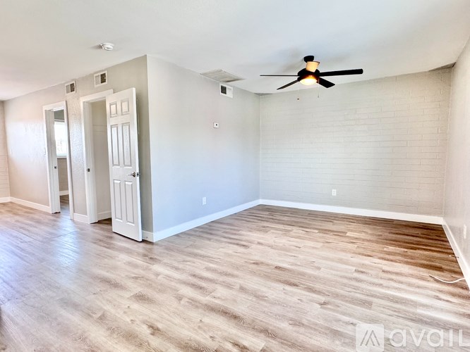 A room with a ceiling fan and wooden flooring.