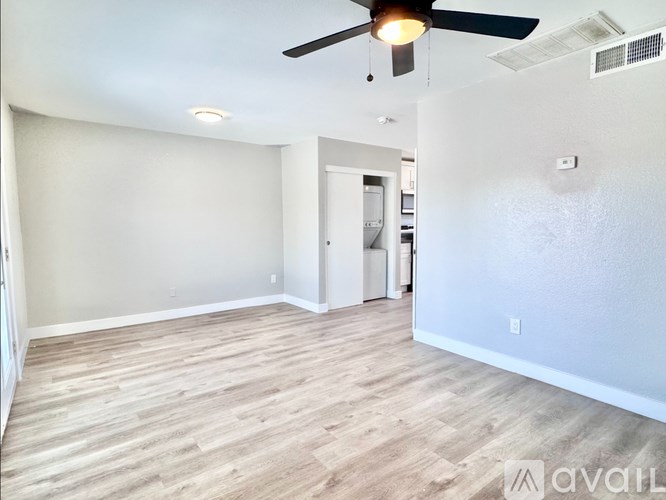 A room with a ceiling fan and light fixture, and a wall-mounted air conditioning unit.