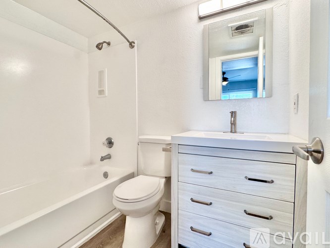 A white bathroom with a toilet, sink, and mirror.