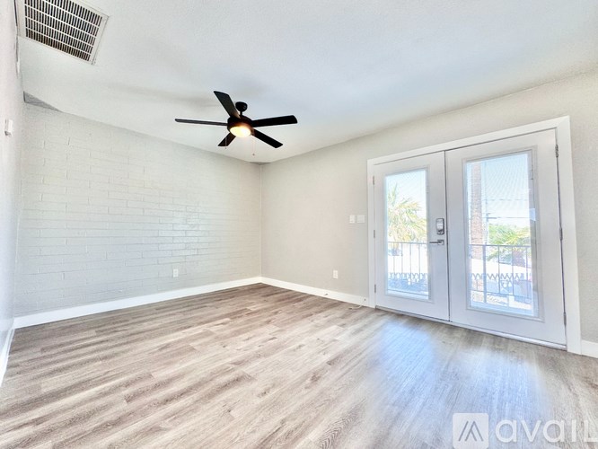 A room with a ceiling fan and sliding glass doors.