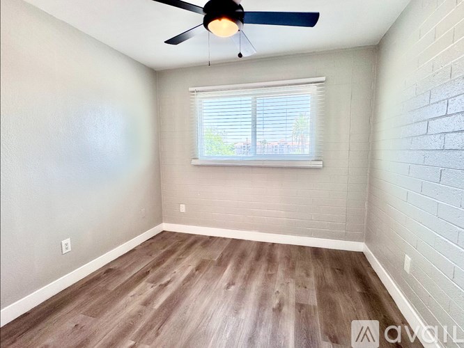 A room with a ceiling fan and wooden flooring.